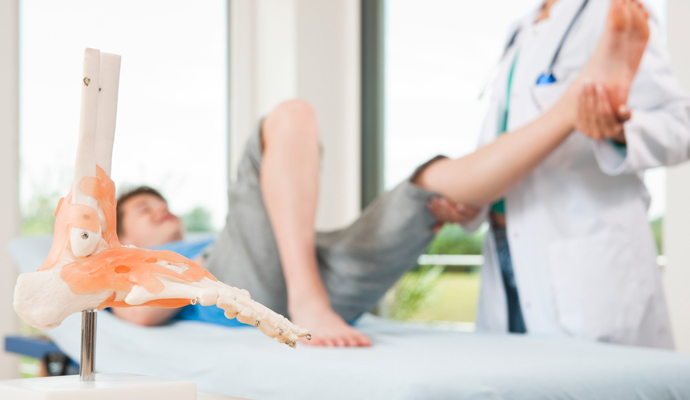 Boy having leg extended by doctor